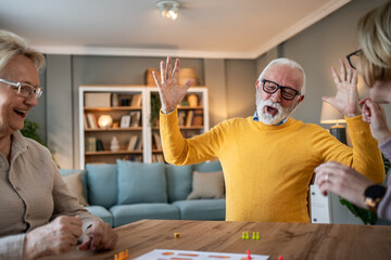 Senior friends enjoying competitive board game at home