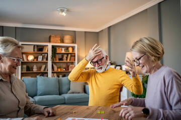 Senior friends enjoying board game night at home
