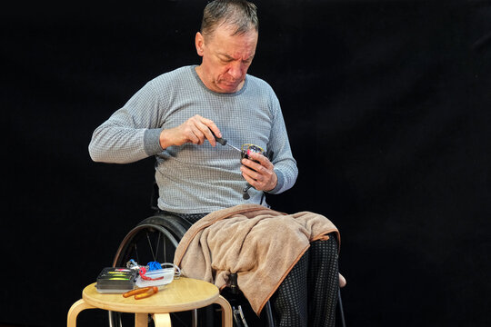 A man in a wheelchair adjusts a spinning reel with a screwdriver