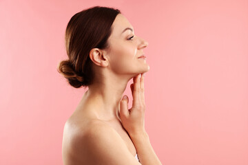 Fototapeta premium Woman touching her neck on pink background