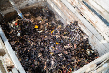 A close-up view of a wooden compost bin filled with decomposing leaves and organic waste.