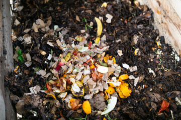 A close-up view of a wooden compost bin filled with decomposing leaves and organic waste.