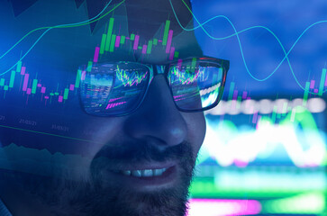 Stock trading data and graphs reflecting in man's glasses. Equity trader or financial analyst working on investment strategy