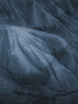 Aerial view of a dramatically textured, monochromatic landscape with deep furrows and subtle gradients creating a stark, geological panorama, Centuripe, Sicilia, Italy.