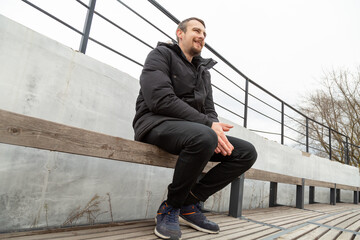 Smile man sitting on bench wearing warm jacket in autumn