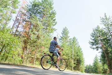 A young father carries his little daughter in a bicycle seat. Dad and child ride a bike in forest