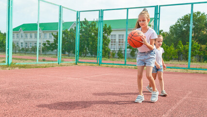 Fototapeta premium summer vacation, sport, games and friendship concept - happy children playing basketball outdoors