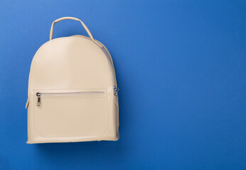 Female fashion beige backpack on color background, top view