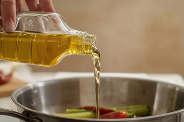 Golden vegetable oil pouring into stainless steel pan in vibrant Thai kitchen
