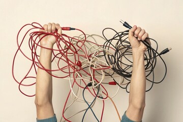 Hands holding tangled cables, symbolizing confusion, wide chaotic layout fits horizontal composition.