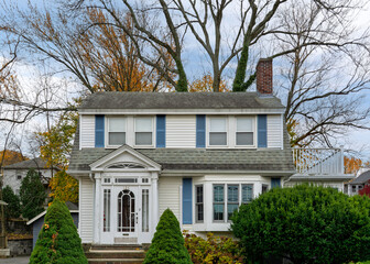 Classic two-story family home with blue shutters and a decorative entryway in a quiet suburban...