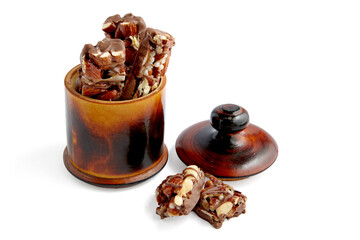 Sweet nutty caramel bars covered with chocolate in a wooden bowl.