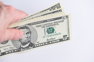 Hand holding five dollar bills in exchange