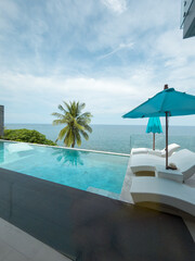 View from luxury villa at sunny day, sun loungers for sunbathing, umbrellas from the sun, pillows for swimming in the pool, palm tree on background