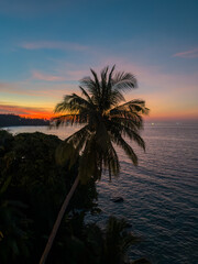 View from luxury villa at dusk, palm tree, sea and orange sky on background, island