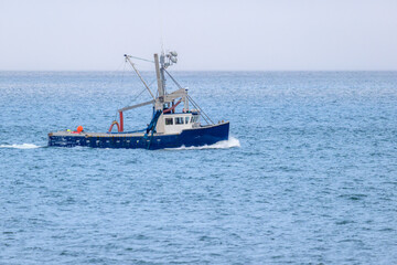 Blue fishing boat motoring across blue water
