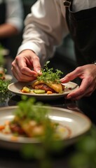Chef garnishes plate with fresh greens. Chef prepares fine dining dish with skill. Focus on food presentation in restaurant kitchen. Plating gourmet meal for service.