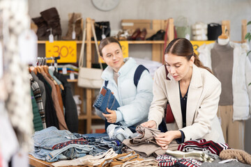 Adult woman and teenage girl choosing trousers in clothing store
