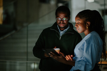 Business colleagues collaborating on tablet during night office work