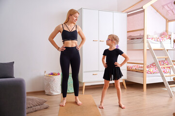 Fototapeta premium Mother and daughter practicing yoga at home
