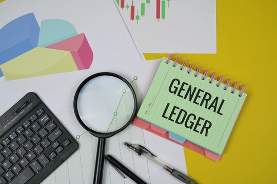 A notebook labeled "General Ledger" sits among charts, a magnifying glass, a keyboard, and pens, suggesting financial analysis, bookkeeping, and data review. isolated on a yellow surface.