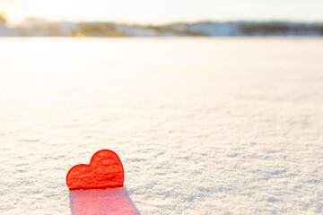 Red heart on a white snowy background. Valentine's Day wallpaper, free space for text. I love winter.