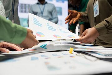 Close up of diverse analysts collaborating on data predictions and projections, exchanging important papers after hours in a meeting. Updating investors with budget and other business intel.