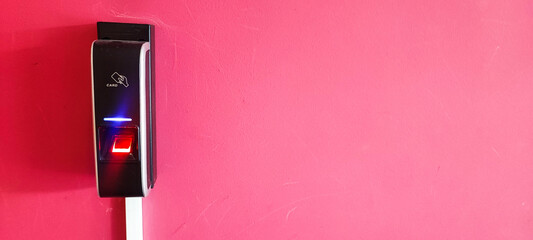 A card reader on a red wall, a hand with a card reaching for the card reader. Concept of modern reading devices