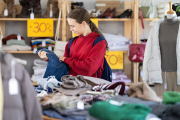 Teenage girl buyer choosing jeans in clothing store