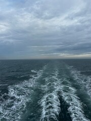 Heckwelle hinter einem Kreuzfahrtschiff bei dramatischem Wolkenhimmel