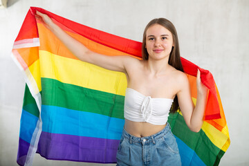 Portrait of a playful girl holding an LGBT flag in her hands