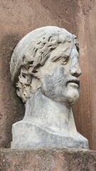 Obraz premium Rome, Italy - 12 January 2025. Worn marble head sculpture with beard and chiseled hair mounted on an exterior wall of Castel Sant’Angelo.