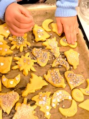Children's hands decorate shortbread cookie dough with stars and sprinkles.