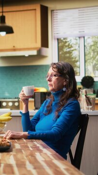 Vertical Video Elderly retired woman ignoring husband and being zoned out, defocused absent person sitting at the table and being preoccupied. Wife being distracted and disconnected during breakfast
