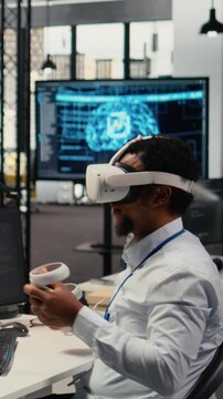 Vertical video Programmer in office using virtual reality tech to fix hacking attempt on corporate network. IT expert uses VR headset to investigate unauthorized access alerts, working to mitigate