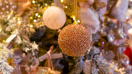 Bright and shiny Christmas toys are hanging on the Christmas tree.