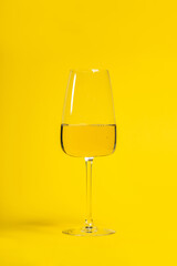 White wine glass on bright yellow background
