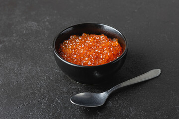 Salmon caviar in a black bowl