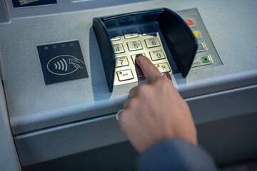 Person entering financial pin on atm keypad