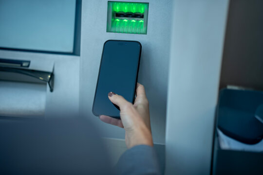 Person using smartphone for cardless atm withdrawal