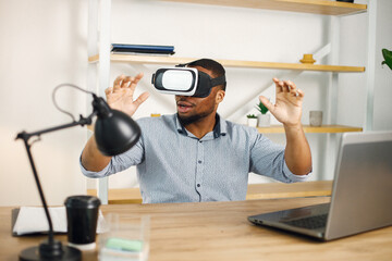 Black male entrepreneur sitting in office and using virtual reality glasses