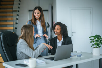 Diverse businesswomen collaborating on laptop during office meeting