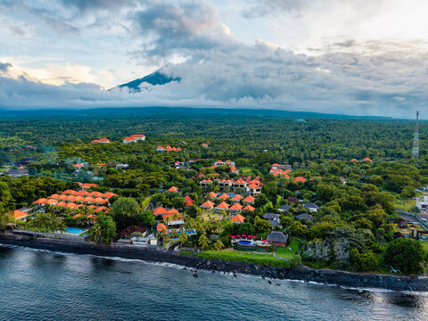 Aerial drone view of Tulamben coast with black sand beach, resort, and Mount Agung