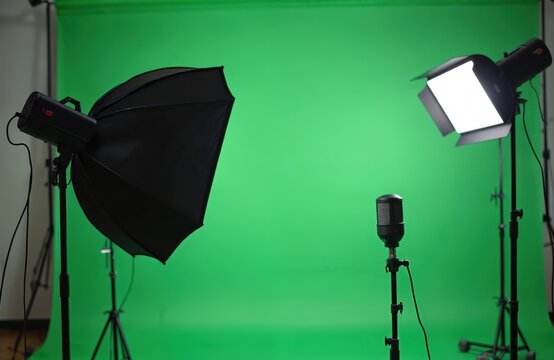 Film studio setup with green screen backdrop, professional microphone, and studio lighting equipment for video production. This space is prepped for filming digital content.