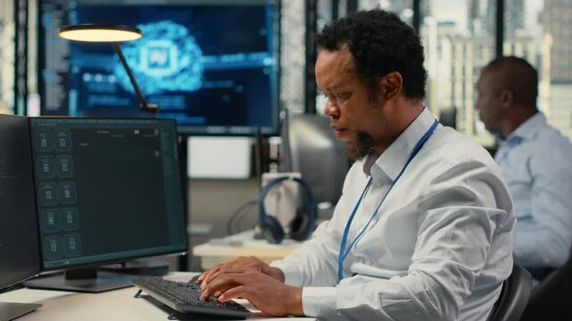 Technician in office solving tasks with artificial intelligence LLM chatbot answering prompts. African american man at work using PC to interact with large language model program, camera B