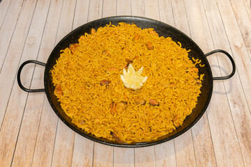 Seafood and chicken paella for two, served in a small individual paella pan, presented on esparto grass trivets with cutlery.