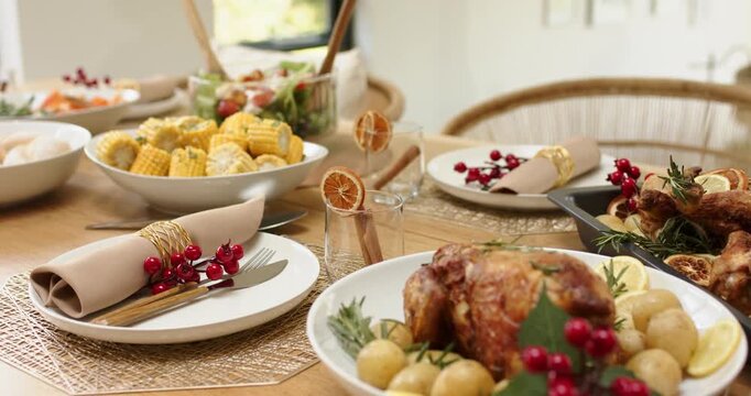 Camera panning chicken garnished with potatoes lemon rosemary revealing spread on wooden table