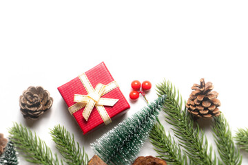 Flat lay Christmas composition with red gift box, pinecones, fir branches, and berries on white background. Ideal for holiday greeting cards, seasonal banners, and winter promotional designs.