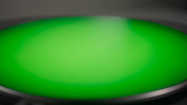 Close-up of a green button with a metallic rim on a dark background