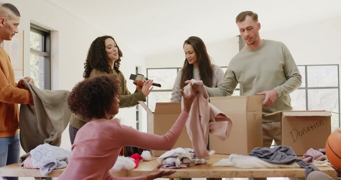 Friends in volunteer room passing tape sorting and folding sweaters into Donation boxes on table